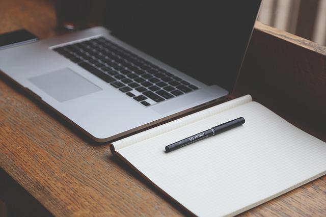Biurko, na którym znajduje się laptop i zeszyt fot. pixabay 